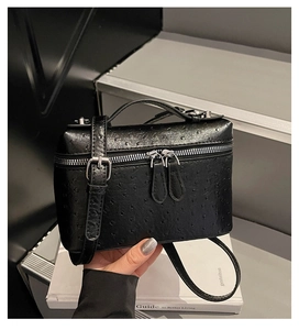 Detail of black ostrich embossed leather small box bag with silver zippers