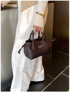 Detail of dark brown lychee leather handbag with decorative drawstrings and dual handles