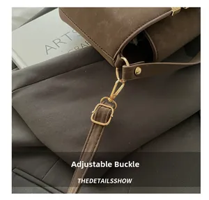 Detail of adjustable golden buckle on dark brown suede shoulder strap for elegant handbag