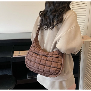 Detail of dark brown quilted crossbody bag with adjustable strap and puffed rhombic texture