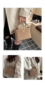 Detailed close-up of earth-toned leather handbag featuring a gold V-shaped metal buckle