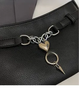 Close-up of black leather baguette bag with silver punk heart charms and metal chains