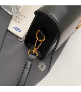 Close-up of durable golden lobster clasp and D-ring on black leather shoulder bag strap