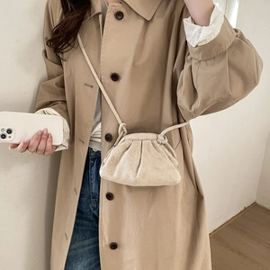 Elegant beige pleated cloud bag worn with trench coat, minimalist crossbody dumplings bag