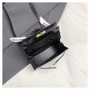 Detail of crocodile embossed leather bag with gold clasp and silk scarf handle decoration