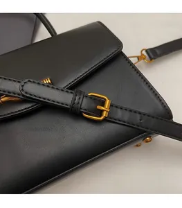 Detail of black leather shoulder bag with adjustable strap and vintage gold buckle hardware