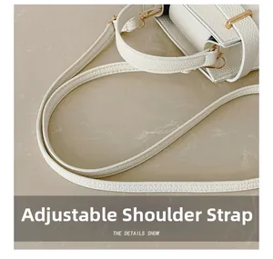 Détail de la bandoulière réglable avec boucle en métal doré sur le sac en cuir blanc