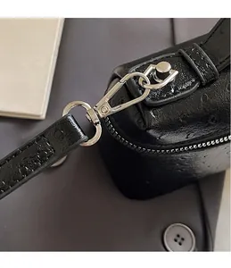 Close-up of silver metal hook and ostrich pattern leather on a black handbag