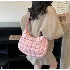 Close-up of pink quilted crescent shoulder bag with puffy texture and adjustable strap