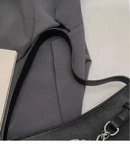 Close-up of black lychee-grain leather texture and smooth long strap on baguette bag