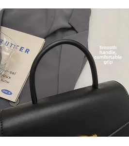 Detail of rounded top handle on black matte leather handbag for comfortable grip