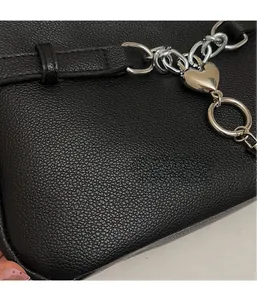 Close-up of black lychee-textured leather bag with silver heart-shaped metal buckle