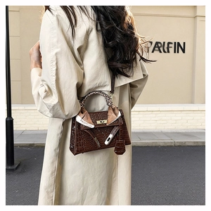 Outdoor shot of a brown crocodile pattern handbag with silk scarf on the handle