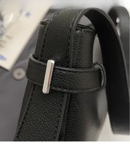 Close-up of black pebble leather handbag featuring polished silver rectangular metal buckle