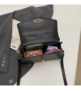 Top view of open black leather crossbody bag showing interior capacity with essentials