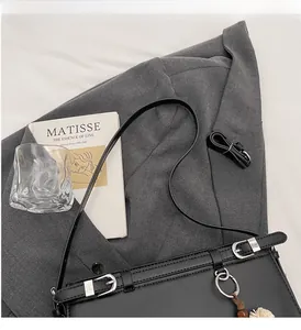 Detail of black leather square bag featuring silver ring buckle and floral charm