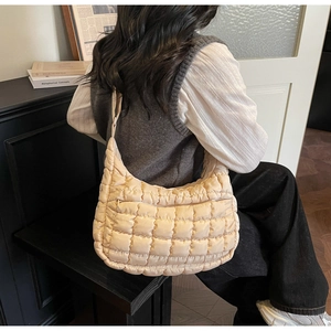 Detail of beige quilted nylon tote bag with puffer texture and premium zipper closure