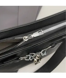 Detail of silver zipper and heart pendant on black litchi pattern leather baguette bag