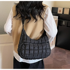 Macro detail of the black quilted texture and durable nylon fabric on the puffy shoulder bag