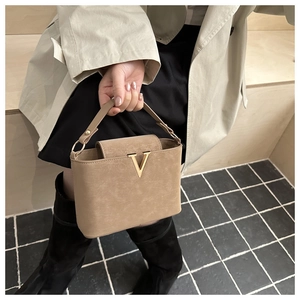 Close-up of khaki bucket bag with luxury suede texture and gold V-shaped metal buckle detail