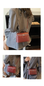 Detail of burgundy ostrich embossed mini box bag with silver zippers and top handle