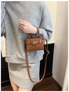 Detailed view of a brown pebbled leather mini crossbody bag with gold turn-lock hardware