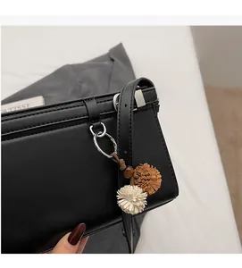 Detail of black leather square bag with silver metal ring and flower charm accessory