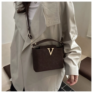 Close-up of vintage brown leather bag with a gold V logo and textured matte finish