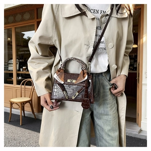 Detail of dark brown croc-effect handbag with silk scarf handle and metal clasp closure