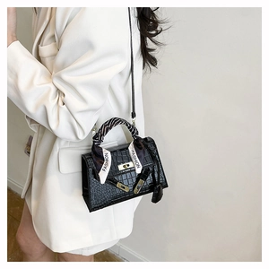 Detail shot of black crocodile embossed handbag with fashion scarf on handle