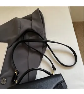 Detail view of black lychee grain leather handbag with golden hardware and adjustable strap