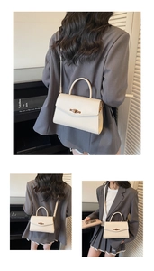 Close-up of cream leather trapezoid handbag with gold eye-shaped twist lock and top handle