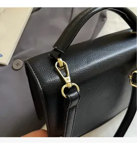 Detailed close-up of golden metal hooks and black leather texture on a chic handbag