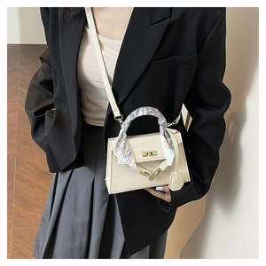 Detailed view of beige crocodile embossed leather bag with silk scarf on the handle