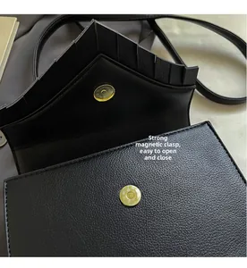 Detail view of black pebble leather texture and secure magnetic snap closure on handbag