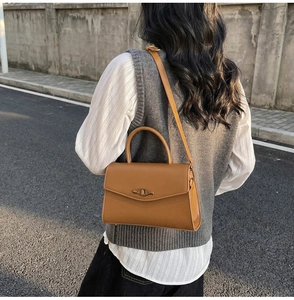 Detail of a brown vintage leather handbag with golden eye-shaped buckle in street setting