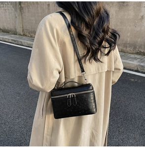 Black ostrich texture box bag with silver hardware worn over a beige trench coat