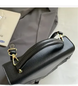 Close-up of pebble leather handbag with reinforced handle and golden metal clasp details