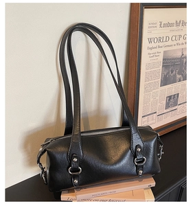 Dettaglio borsa a cilindro nera retrò su libri vintage con tracolle lunghe e fibbie