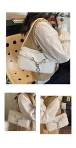 Detail of white faux leather underarm bag featuring silver chain and heart pendant