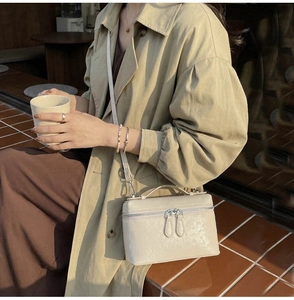 On-model shot of cream ostrich-pattern crossbody box bag with silver zippers