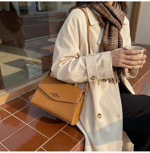 Close-up of brown leather bag featuring a vintage gold metal clasp on model shoulder