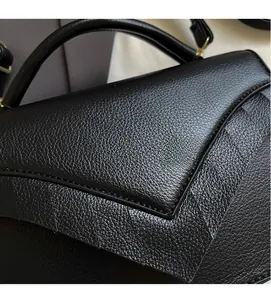 Close-up of black lychee grain leather handbag featuring geometric flap and stitching