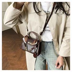 Detail of dark brown croc-effect handbag with gold lock and silk scarf accessory