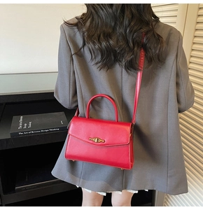 Rear view of a chic red leather handbag with vintage gold twist-lock on a model