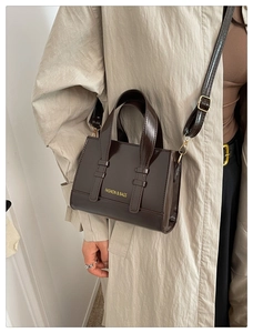Detail of dark brown patent leather square bag with high-gloss finish and adjustable strap