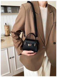 Elegant black lychee texture handbag with gold twist lock shown on model in modern kitchen