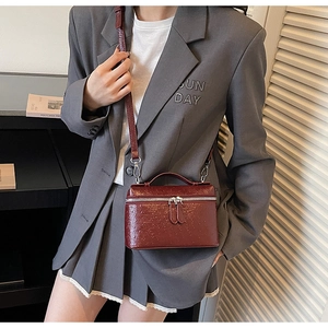 Detail of burgundy ostrich embossed square crossbody bag with silver hardware and top handle