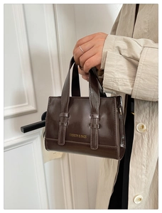 Detail of dark brown glossy handbag with vertical straps and golden fashion logo