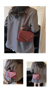 Detail of burgundy crossbody bag with V-shaped tassel decoration and sleek leather texture